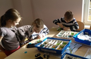 kaks tüdrukut ja üks poiss ehitavad programmeeritavaid legomasinaid